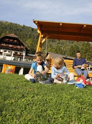 Two children sitting on the lawn in the hotel garden of Hotel Ramsi - in the background their father is sitting in a Hollywood swing.