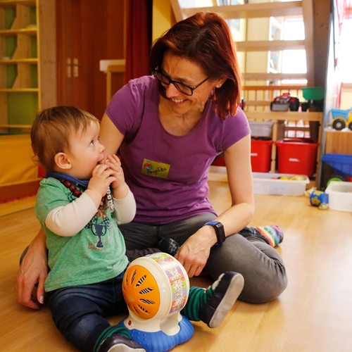 Ramsi caregiver laughing and playing with toddler in the colorful playroom.