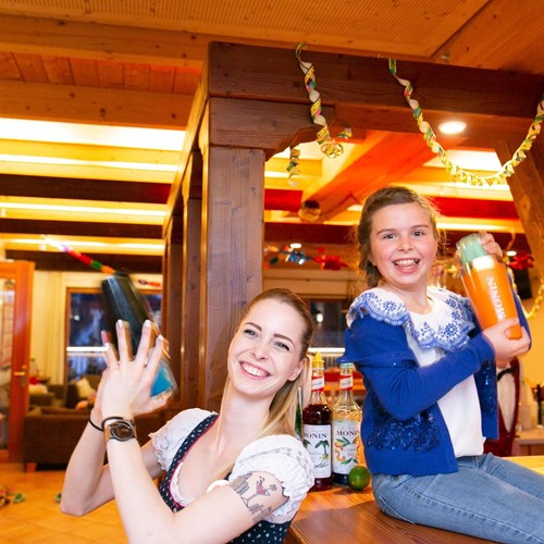Girls and Ramsi supervisor shake colorful mocktails laughing at the bar decorated with streamers.